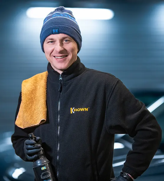 Uśmiechnięty mężczyzna z recznikiem na barku i płynem w ręku